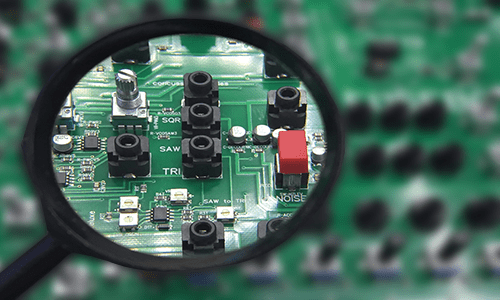 Magnifying glass inspecting a PCB